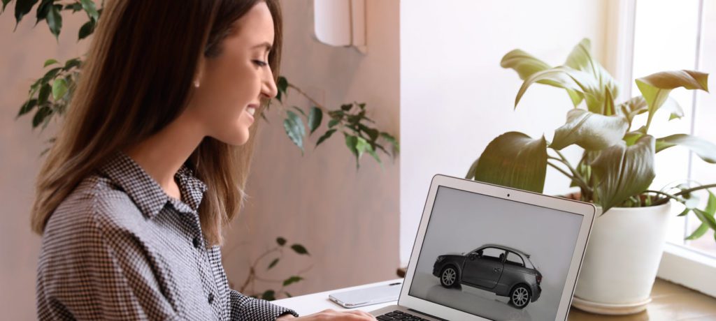 A woman looks at a car image on her laptop